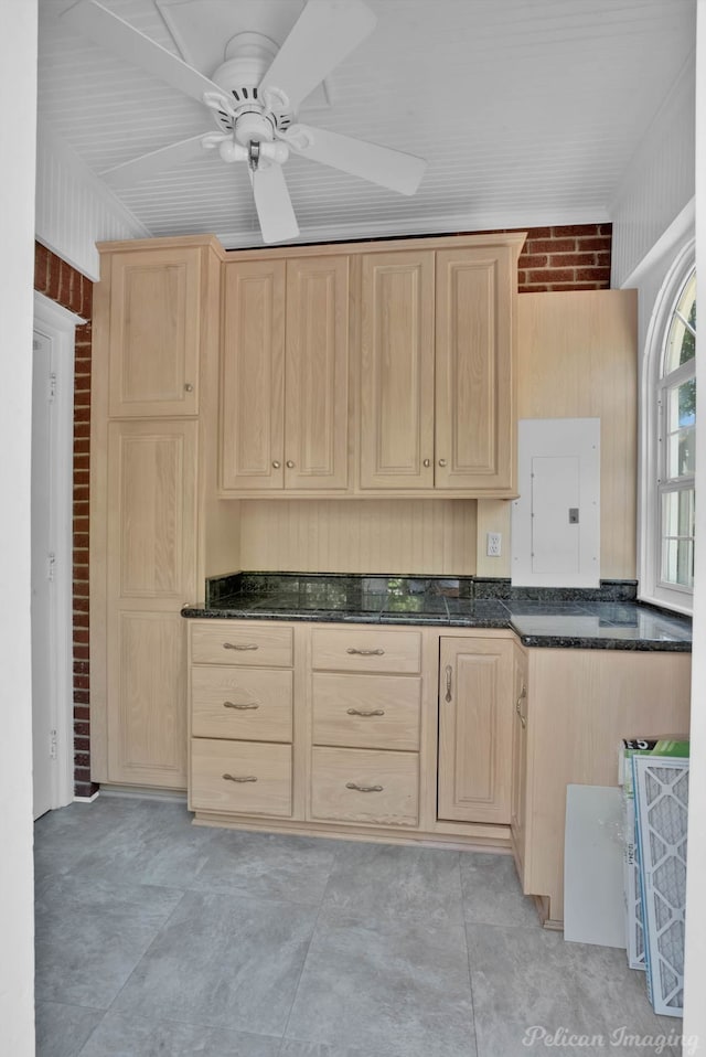 kitchen featuring ceiling fan, light brown cabinets, and brick wall