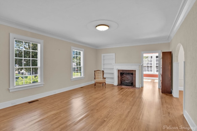 unfurnished living room with a fireplace, light hardwood / wood-style floors, built in features, and crown molding