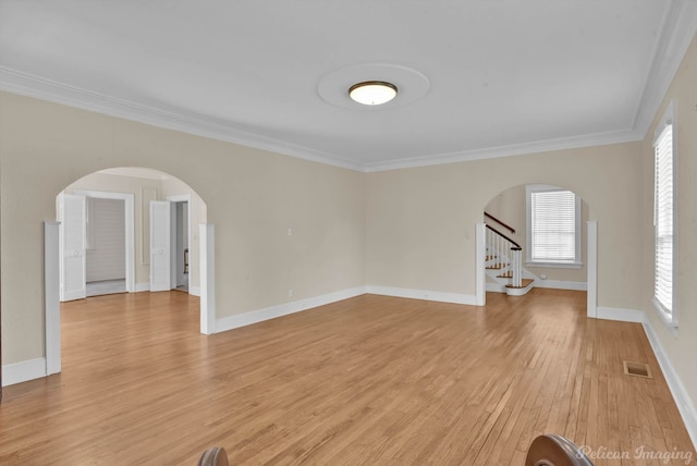 empty room featuring plenty of natural light, light hardwood / wood-style floors, and ornamental molding