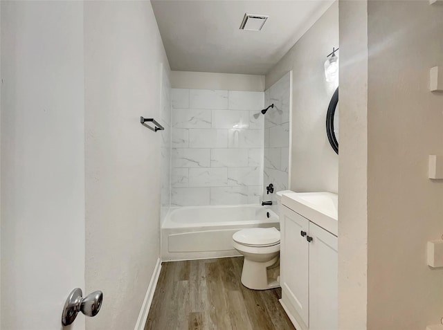 full bathroom with hardwood / wood-style floors, vanity, tiled shower / bath combo, and toilet