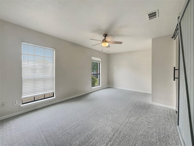 empty room with ceiling fan, carpet, and a healthy amount of sunlight