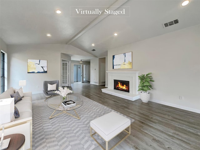 living room with vaulted ceiling with beams, wood-type flooring, and a fireplace