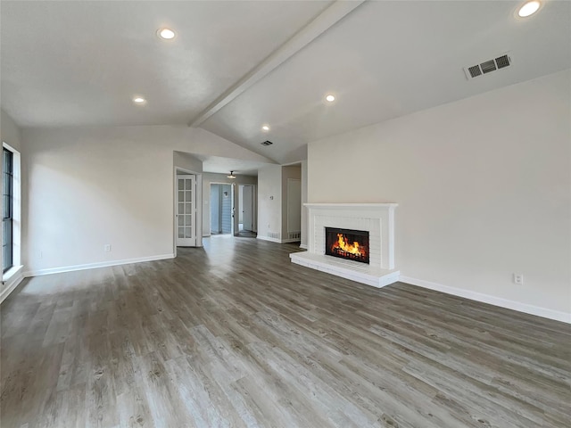 unfurnished living room featuring lofted ceiling with beams, hardwood / wood-style flooring, and a brick fireplace