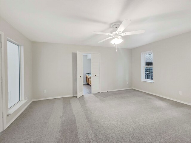 unfurnished bedroom featuring ensuite bath, ceiling fan, and light colored carpet