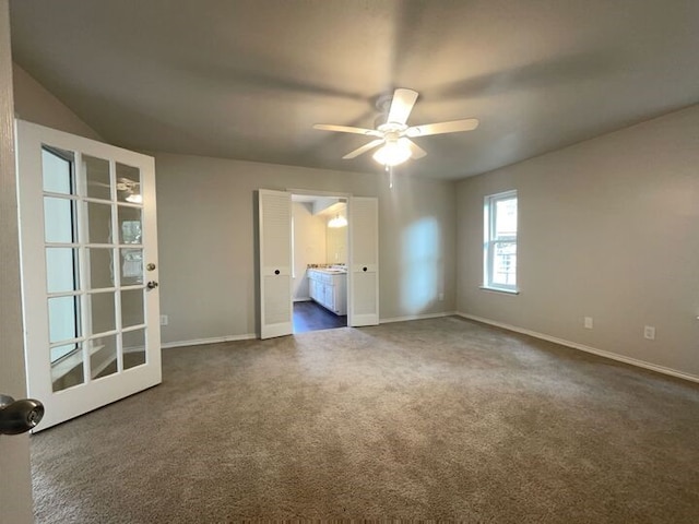 unfurnished bedroom with dark carpet, ceiling fan, and ensuite bathroom