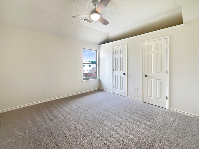 unfurnished bedroom with lofted ceiling, ceiling fan, carpet floors, and a textured ceiling