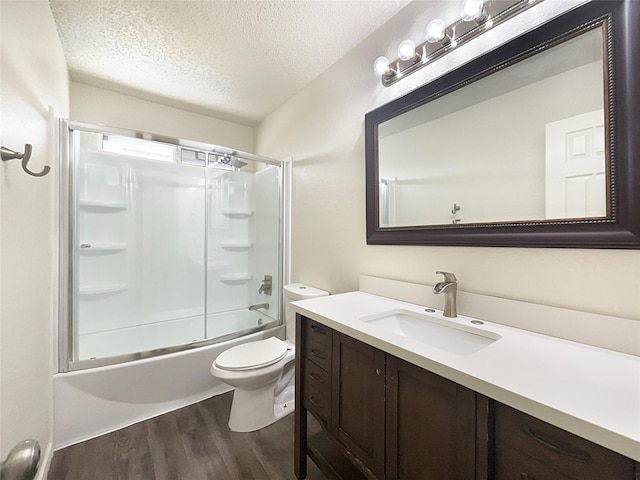 full bathroom with bath / shower combo with glass door, wood-type flooring, a textured ceiling, toilet, and vanity