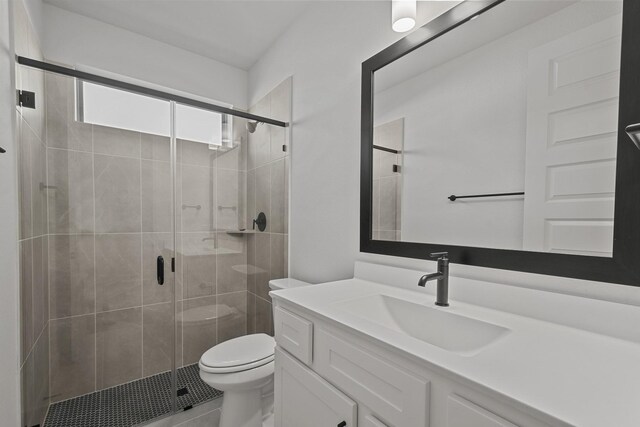 bathroom featuring vanity, toilet, and a shower with door