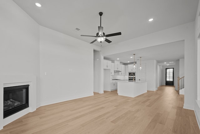 unfurnished living room featuring light wood-type flooring and ceiling fan