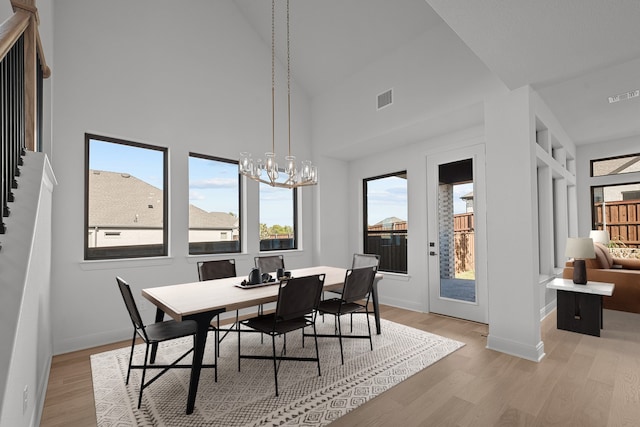 dining space with high vaulted ceiling, a chandelier, and light wood-type flooring