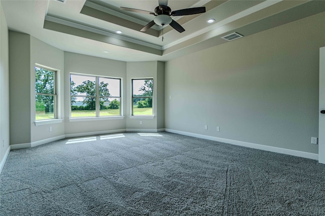 unfurnished room featuring a raised ceiling, ceiling fan, carpet, and ornamental molding