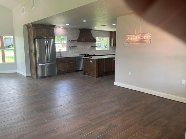 kitchen featuring dark wood-type flooring, range, sink, stainless steel fridge, and custom range hood