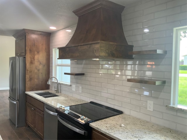 kitchen featuring light stone countertops, appliances with stainless steel finishes, custom exhaust hood, and sink