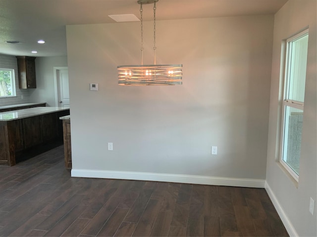 unfurnished dining area with a notable chandelier and dark hardwood / wood-style flooring