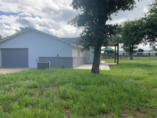 view of side of property with a yard, cooling unit, and a garage