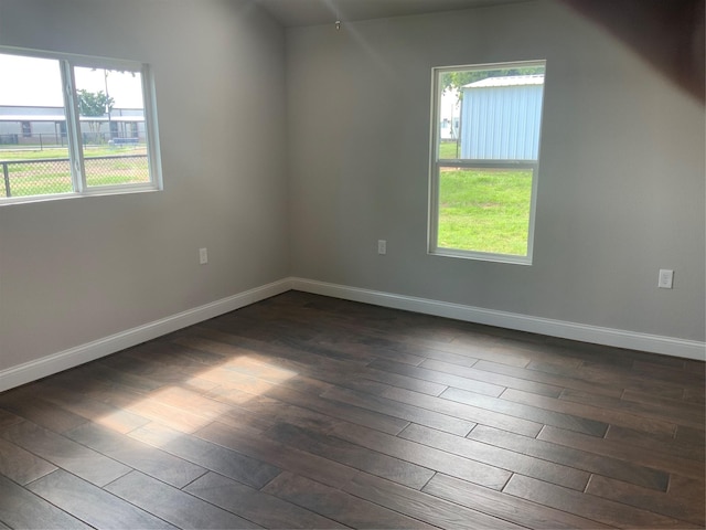 empty room featuring plenty of natural light and dark wood-type flooring