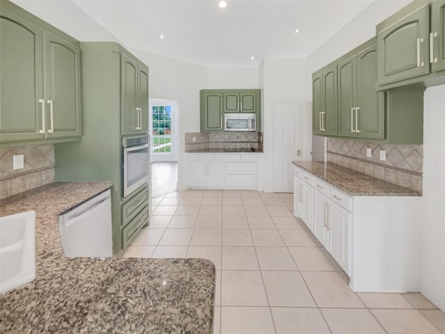 kitchen with decorative backsplash, light stone countertops, white appliances, green cabinetry, and light tile patterned flooring