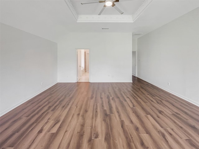 empty room with dark hardwood / wood-style floors, ceiling fan, a raised ceiling, and ornamental molding