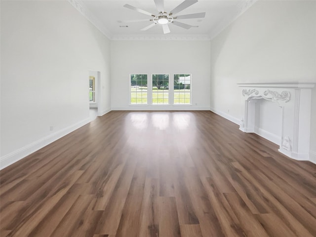 unfurnished living room featuring ceiling fan, crown molding, a towering ceiling, and dark wood-type flooring