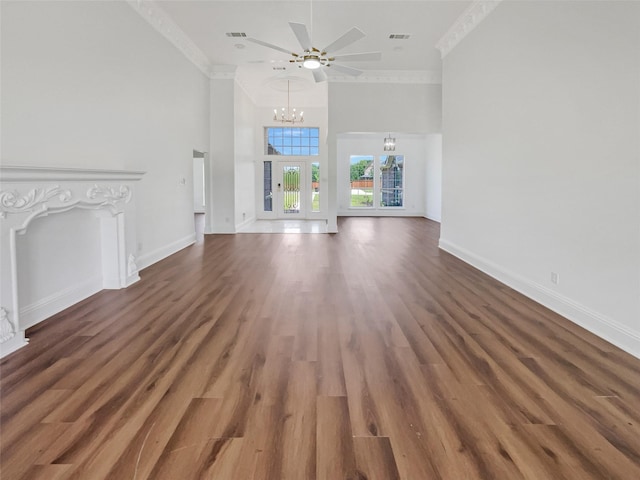 unfurnished living room with crown molding, dark wood-type flooring, a high ceiling, and a chandelier