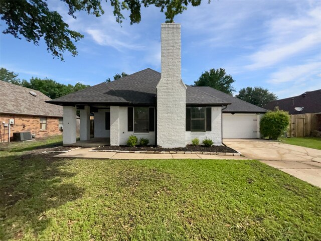 single story home with a chimney, a front yard, and concrete driveway