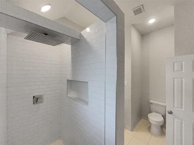 bathroom with tile patterned floors, tiled shower, and toilet