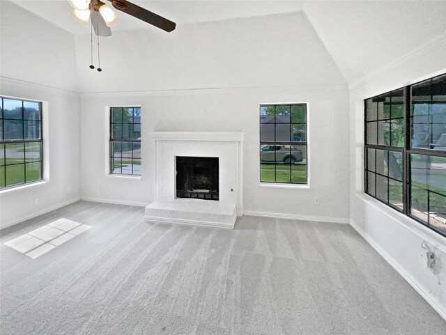 unfurnished living room with lofted ceiling, a ceiling fan, plenty of natural light, a warm lit fireplace, and wood finished floors