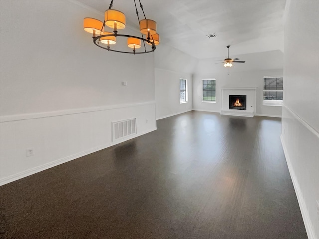 unfurnished living room featuring ceiling fan with notable chandelier and vaulted ceiling