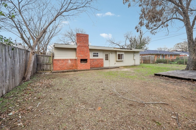 back of property featuring a fireplace, a deck, and a yard