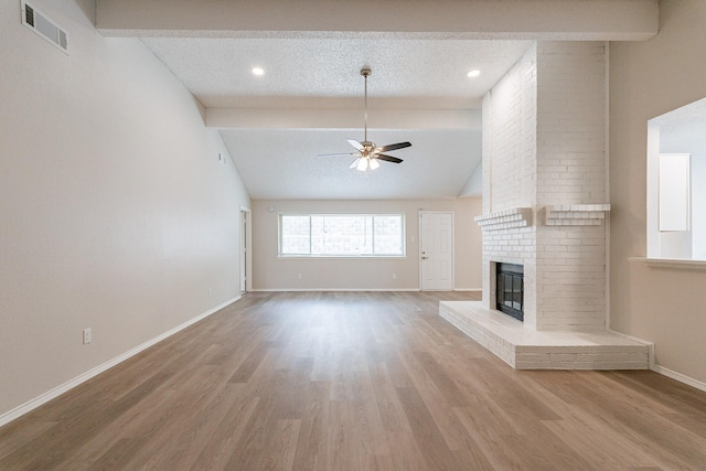 unfurnished living room with ceiling fan, vaulted ceiling with beams, a fireplace, and a textured ceiling