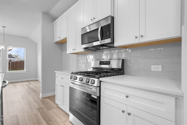 kitchen featuring pendant lighting, white cabinetry, stainless steel appliances, an inviting chandelier, and decorative backsplash