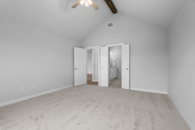 unfurnished bedroom featuring beamed ceiling, high vaulted ceiling, ensuite bath, ceiling fan, and light colored carpet