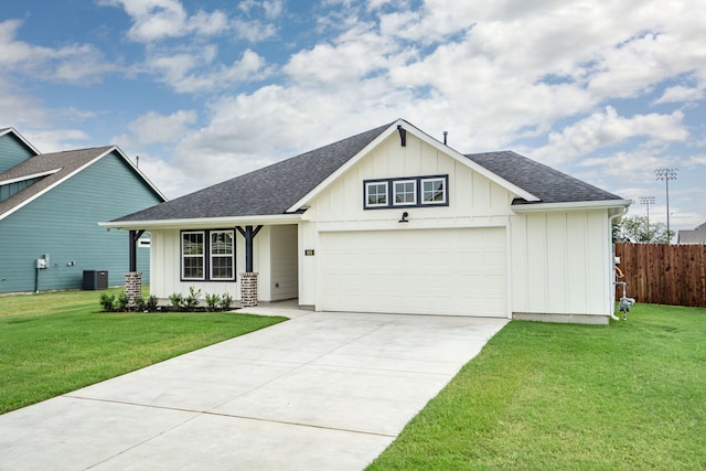 view of front of house with central AC, a garage, and a front lawn