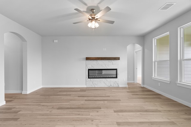 unfurnished living room featuring ceiling fan, a high end fireplace, and light hardwood / wood-style flooring