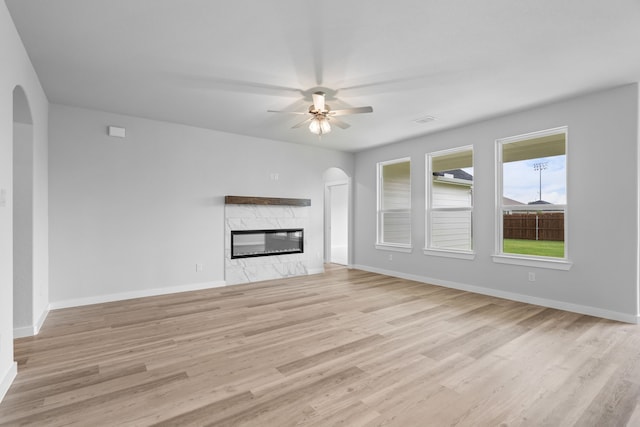 unfurnished living room featuring light hardwood / wood-style flooring, ceiling fan, and a fireplace