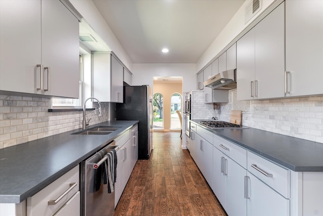 kitchen featuring decorative backsplash, dark hardwood / wood-style flooring, stainless steel appliances, extractor fan, and sink