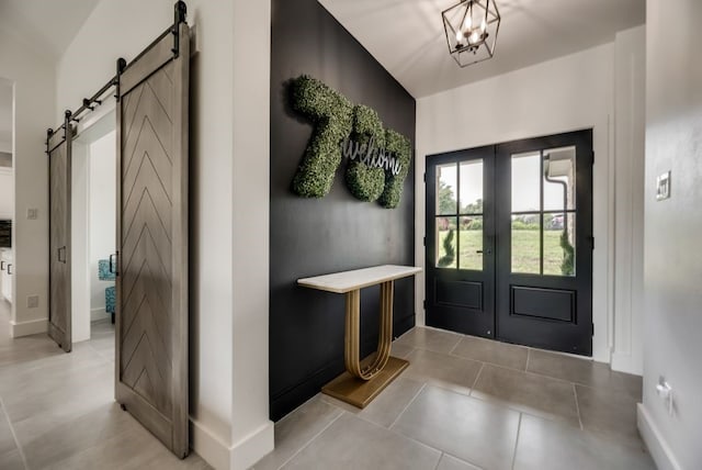 entryway with a barn door, french doors, light tile flooring, and a chandelier