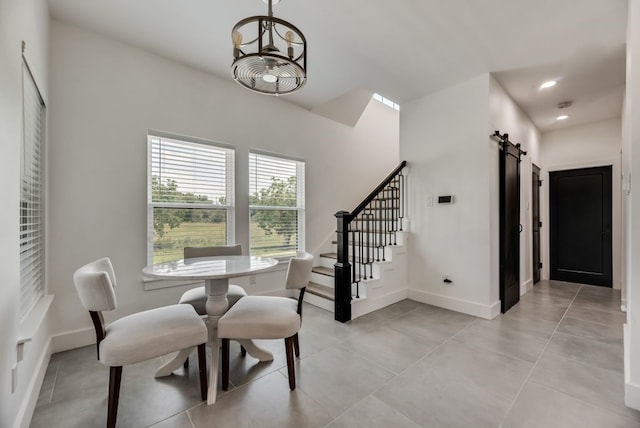 tiled dining space featuring a barn door and a notable chandelier