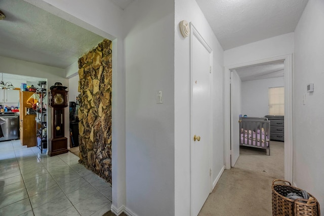 corridor featuring a textured ceiling and light carpet