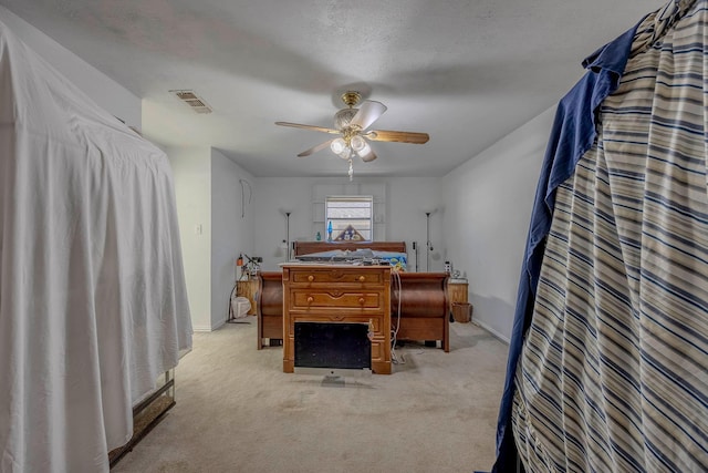 bedroom with a textured ceiling, ceiling fan, and light carpet