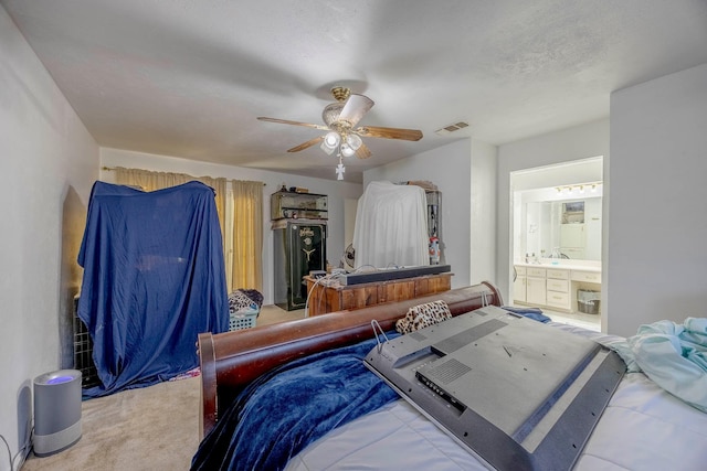 bedroom featuring ensuite bath, ceiling fan, light colored carpet, and a textured ceiling