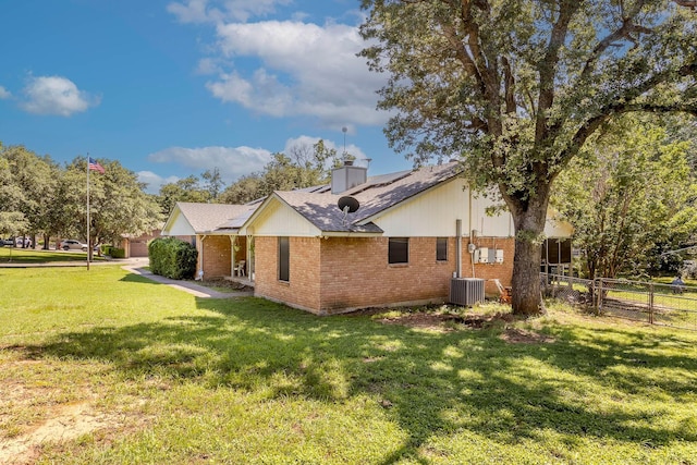 view of side of property with a yard and central AC