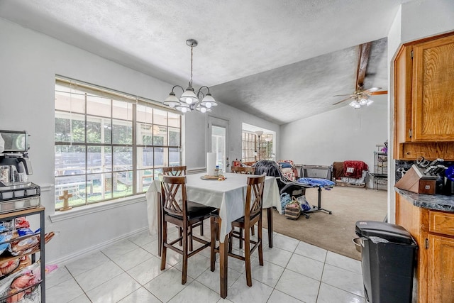 dining room with vaulted ceiling with beams, ceiling fan with notable chandelier, light tile patterned floors, and a textured ceiling