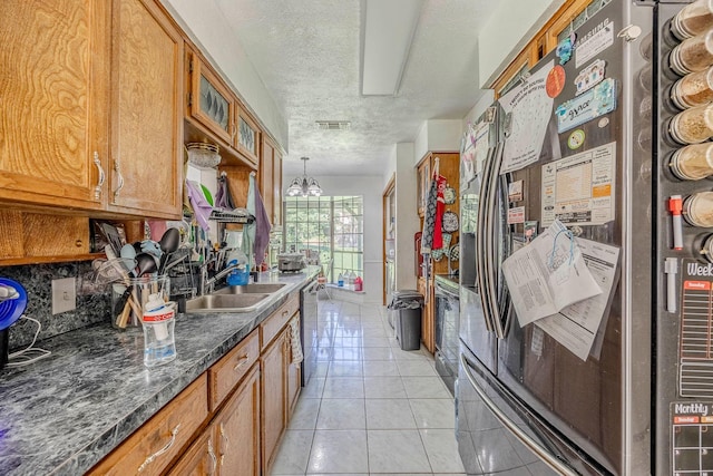 kitchen with appliances with stainless steel finishes, sink, pendant lighting, an inviting chandelier, and light tile patterned flooring