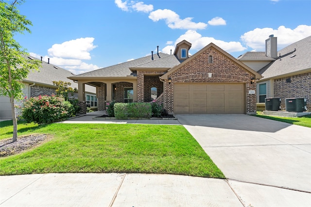 view of front of property featuring a garage, a front yard, and central air condition unit