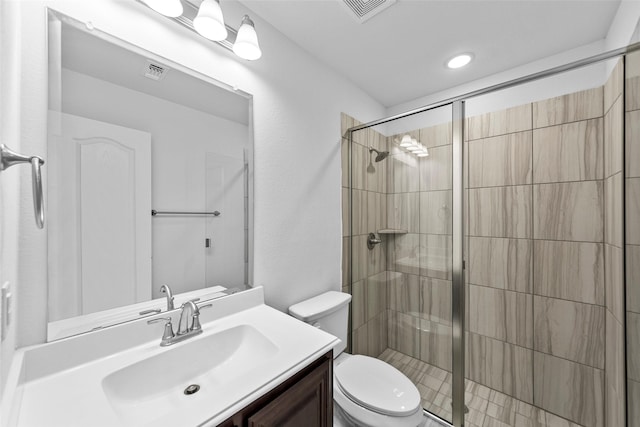 bathroom featuring a shower with door, vanity, and toilet