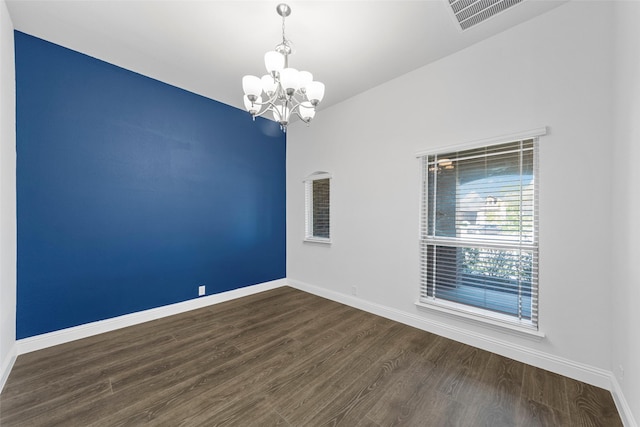 empty room featuring dark hardwood / wood-style floors and an inviting chandelier