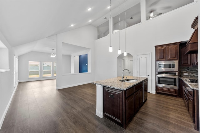 kitchen with light stone counters, appliances with stainless steel finishes, sink, and hanging light fixtures