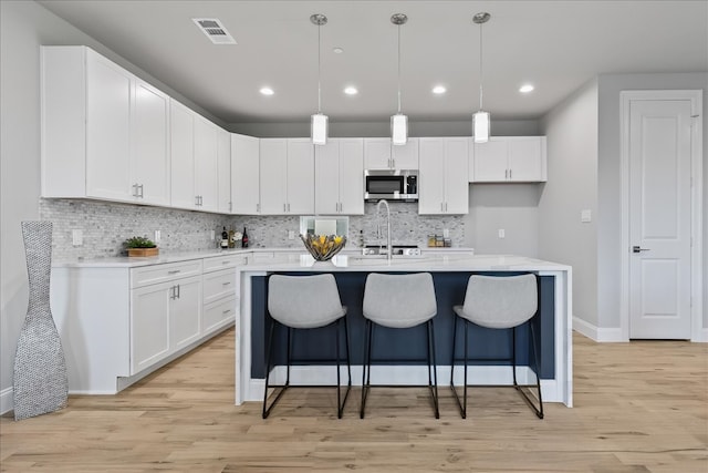 kitchen featuring hanging light fixtures, white cabinetry, and light hardwood / wood-style flooring