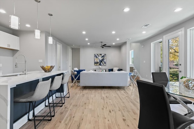 dining area with light hardwood / wood-style flooring, sink, and ceiling fan